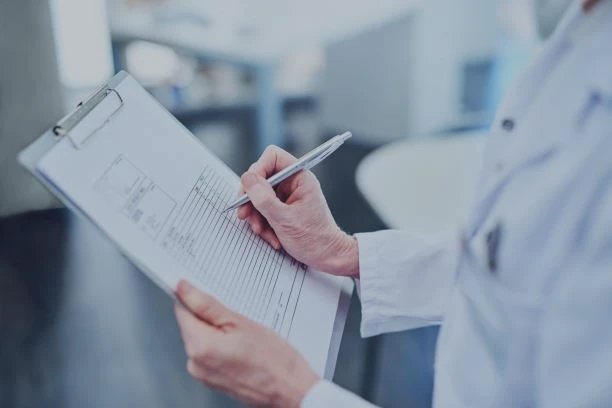 Doctor filling out a paper medical form.